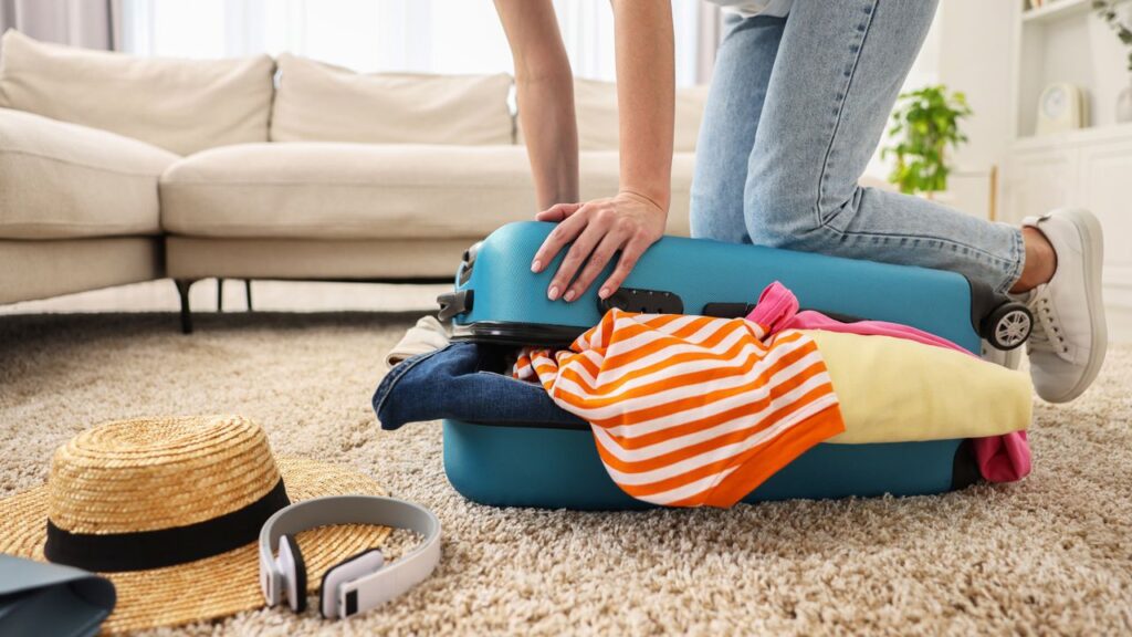 Woman,Packing,Suitcase,For,Trip,On,Floor,Indoors,,Closeup