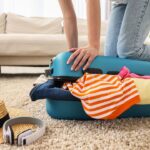 Woman,Packing,Suitcase,For,Trip,On,Floor,Indoors,,Closeup