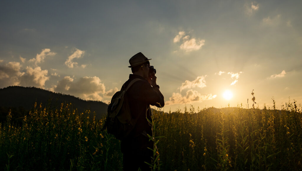 Silhouette of a young who like to travel and photographer, takin