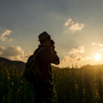 Silhouette of a young who like to travel and photographer, takin