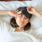 High angle view of young woman hate to wake up in the morning and she wearing sleep mask during sleeping on the bed.