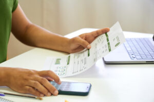 Close-up view of a woman calculating house bills with a mobile phone.